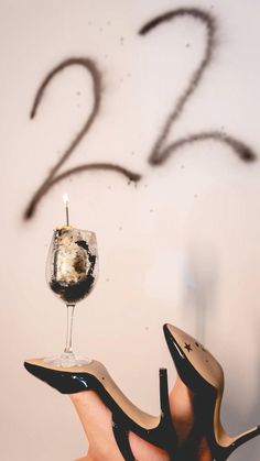 a woman's hand holding a wine glass with the number twenty two on it