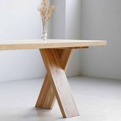 a wooden table with a vase on top of it and flowers in the middle of the table