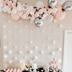 a table topped with cakes and desserts next to a wall covered in snowflakes