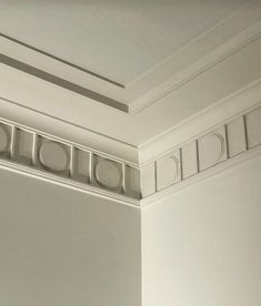 the corner of a room with white walls and decorative moldings on the trimming