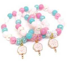 three bracelets with charms and beads on white background, one is pink, the other is blue