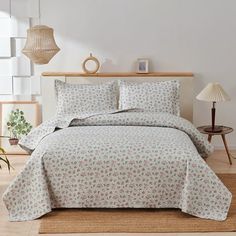 a bed in a room with white walls and wooden flooring next to a lamp