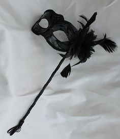 Stunning Black Masquerade Mask on a Stick with a flower made of black fabric petals, feathers and black and white organza $18.15  Handmade, Plastic, wood, paint with a tassel  Depth of Mask is 3”  Arrives 10-18 days later - Ships from the UK Black Masquerade Mask For Mardi Gras Costume Party, Black Venetian Masquerade Mask For Carnival, Black Masks And Prosthetics For Mardi Gras Costume, Elegant Black Costume Accessories For Mardi Gras, Black Masquerade Mask For Carnival Costume Party, Black Venetian Masks For Carnival, Black Costume Accessories For Masquerade Carnival, Black Venetian Masks And Prosthetics For Mardi Gras, Gothic Black Masquerade Mask For Mardi Gras