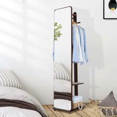 a mirror sitting on top of a wooden floor next to a bed and pillow cases