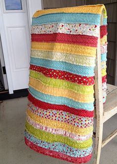 a multicolored blanket sitting on top of a wooden chair next to a white door