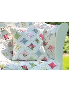 a close up of a pillow on a couch in the grass with trees in the background