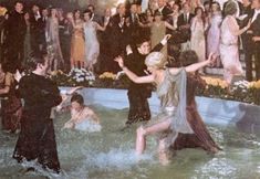 a group of people are dancing in the water at a formal event with other people watching