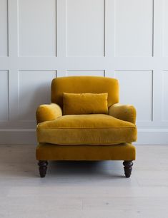 a yellow chair sitting in front of a wall with white paneling on the walls