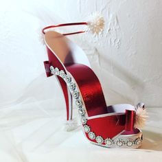 a red high heeled shoe is adorned with crystal beads and pearls, along with a white pom - pom