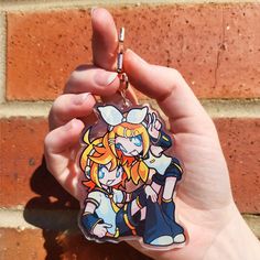 a hand holding a keychain with an anime character on it