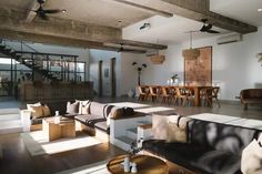 a living room filled with lots of furniture next to a wooden table and stairs in the background