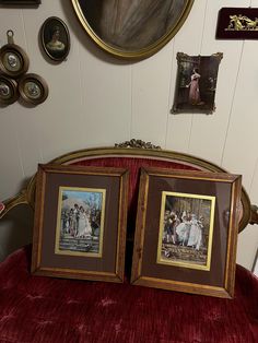 two framed pictures sitting on top of a red velvet covered bed next to a wall