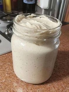 a jar filled with whipped cream sitting on top of a counter next to a stove