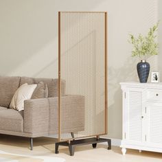 a living room with a beige couch and white cabinet next to a wall mounted screen