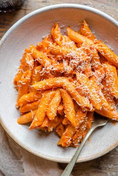 a white bowl filled with pasta covered in parmesan cheese