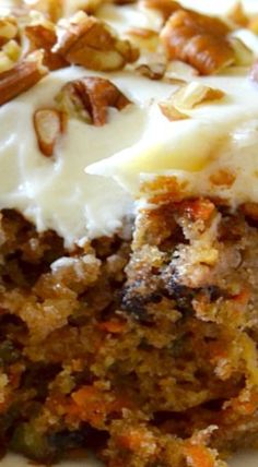 a piece of carrot cake with white frosting and nuts