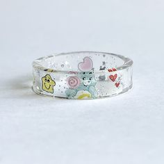 Custom wish Care Bear ring Please make sure to size your finger I will no longer be accepting exchanges as I have to pay for the shipping to send the new size.  Thank you ♥️ & I hope you understand  This adorable ring is so unique.  I made this ring for a customer and she was in love with this item.  So I decided to post it as a listing.  I can't wait to make yours! This ring is unique so no two are the same. The smaller the ring size you may only see half of the belly design Shipping says 5-7 days however most of the time I get the order out within a few days. Colors may be a little lighters however I have and am working on adding non edited photos and videos to all care Bear listings. Very dainty and unique Whimsical Adjustable Rings, Fun Clear Jewelry As Gift, Fun Clear Jewelry For Gifts, Fun Clear Jewelry As A Gift, Cute White Rings For Gifts, Cute Hypoallergenic Clear Jewelry, Cute Resin Jewelry For Birthday, Cute Multicolor Rings For Gift, Cute Resin Jewelry For Birthdays