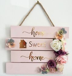 a sign that says home sweet home with flowers hanging on the wall next to it