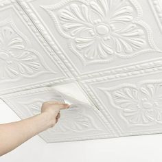 a person is painting the ceiling with white paint and some decorative tiles on top of it