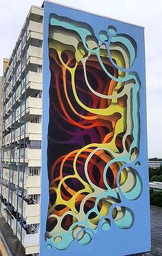 a tall building with a colorful mural on it's side next to a parking lot