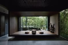 an empty room with two couches in front of the sliding glass doors and bamboo trees