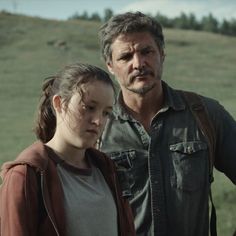 a man and a woman standing next to each other in front of a green field