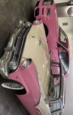 a pink and white car parked next to each other in a room with tile flooring