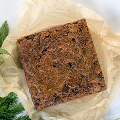 a piece of brownie sitting on top of a table next to some green leaves