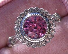 a ring with a pink stone surrounded by diamonds