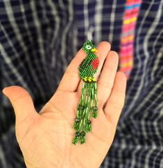 Expertly crafted with intricate beadwork, these Large Beaded Quetzal Earrings embody the beauty and culture of Guatemala. The dainty green and red design adds a stunning touch to any outfit, making them a unique and elegant accessory for any occasion. Embrace the unparalleled craftsmanship and representation of Guatemalan culture with these stylish earrings. Measurements: 4.5 inches long 0.90 inches wide Traditional Dangle Jewelry With Bead Caps, Traditional Green Beads For Festival, Artisan Green Jewelry With Tiny Beads, Traditional Green Beaded Necklaces With Dangling Beads, Traditional Green Beaded Necklace With Dangling Beads, Green Artisan Dangling Beads, Artisan Green Dangling Beads, Traditional Green Beaded Jewelry, Bohemian Green Dangle Beads