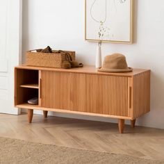 a wooden cabinet sitting next to a white wall with a hat on top of it