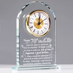 a clear glass clock with the words happy 70th birthday written in gold and white on it