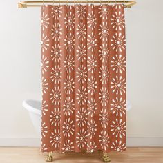 a shower curtain with an orange and white flower pattern on it, in front of a bathtub