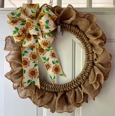 a wreath with sunflowers on it hangs from the front door, decorated with burlap