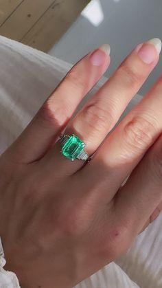 a woman's hand with an emerald and diamond ring