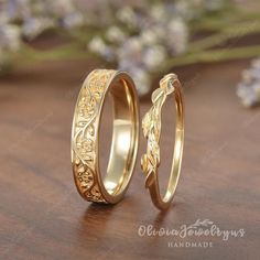 two gold wedding rings sitting on top of a wooden table