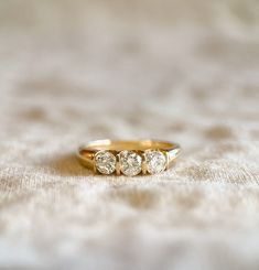 three stone ring sitting on top of a white cloth