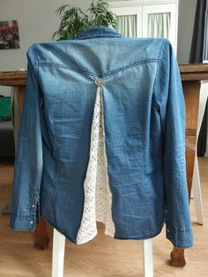 the back of a denim jacket with lace on it, sitting on top of a wooden table