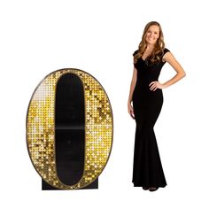 a woman in a black dress standing next to a large letter o with gold sequins