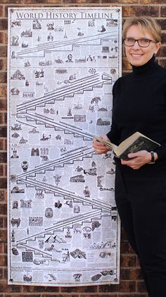 a woman standing in front of a poster holding a book