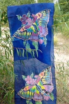 an image of two butterflies on a blue background hanging from a tree branch in the woods