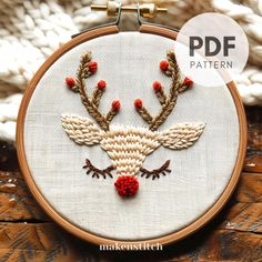 an embroidered deer head with red berries on it's antlers is shown in the hoop