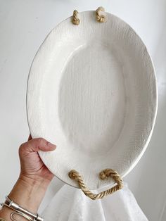 a person holding up a white plate with rope on it