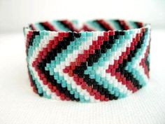 a close up of a bracelet on a white surface with red, blue and black beads