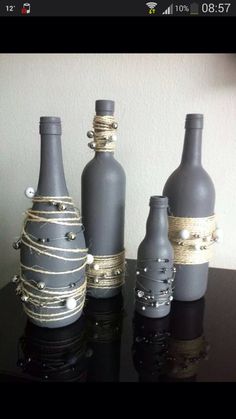 three gray bottles with rope wrapped around them sitting on a black counter top next to a white wall