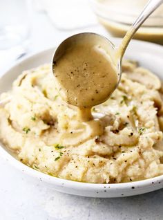 a spoon full of mashed potatoes with gravy