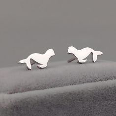 two silver cufflinks with white horses on them sitting on top of a hill