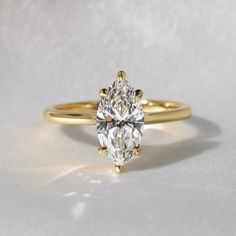 a yellow gold engagement ring with a pear shaped diamond in the center on a white background