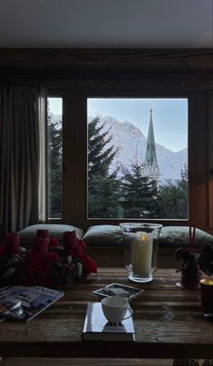 a living room filled with furniture and a large window covered in frosty snow capped mountains