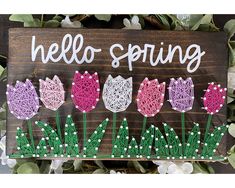 a wooden sign that says hello spring with tulips